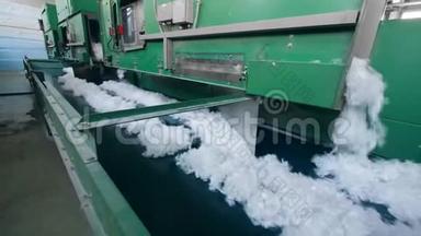 工厂机器使用白色聚酯纤维，将其移动到输送机上。